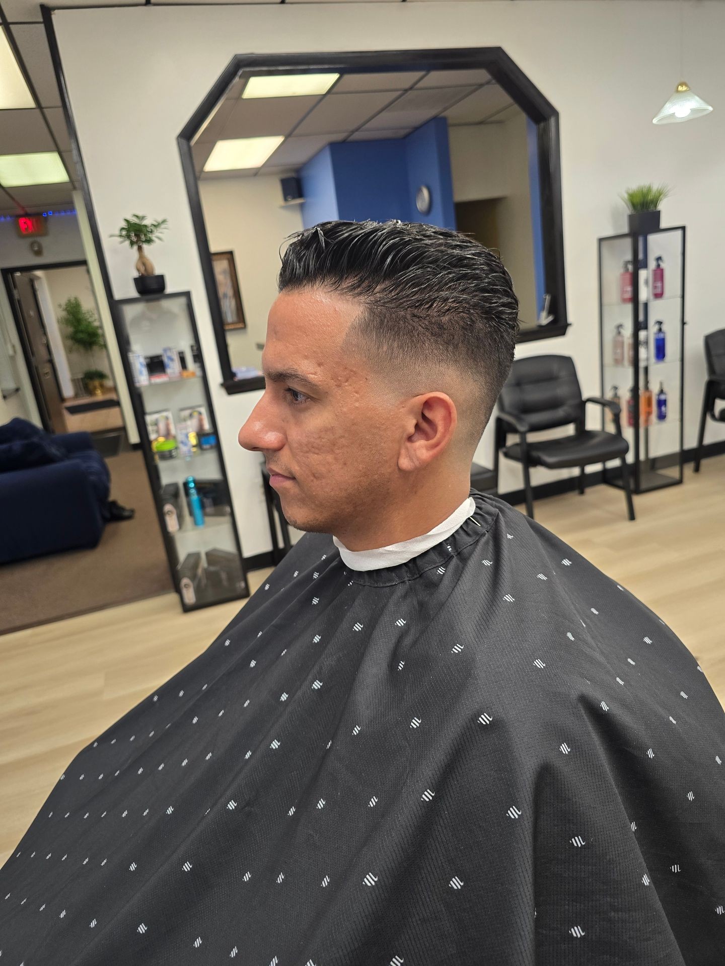 Side profile of a person with a fresh haircut in a barbershop.