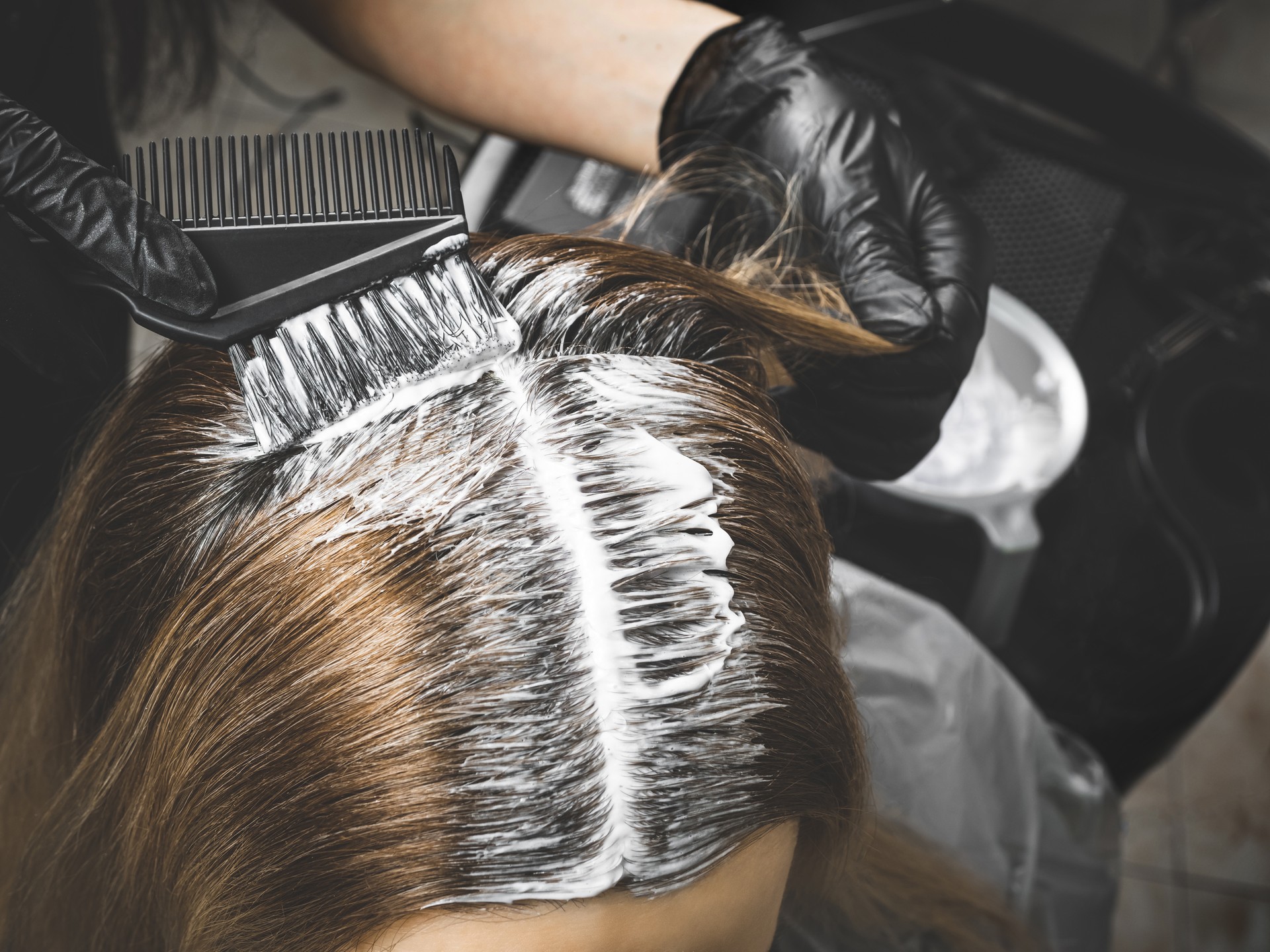 Hairdresser is applying bleaching powder on woman's hair