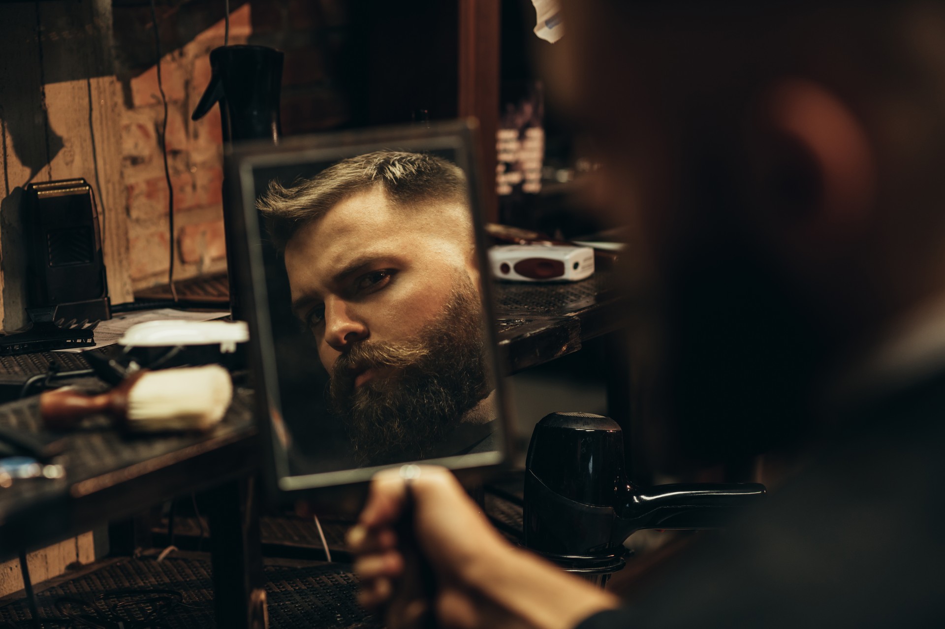 Man looking herself in the mirror while sitting in chair at a barbershop